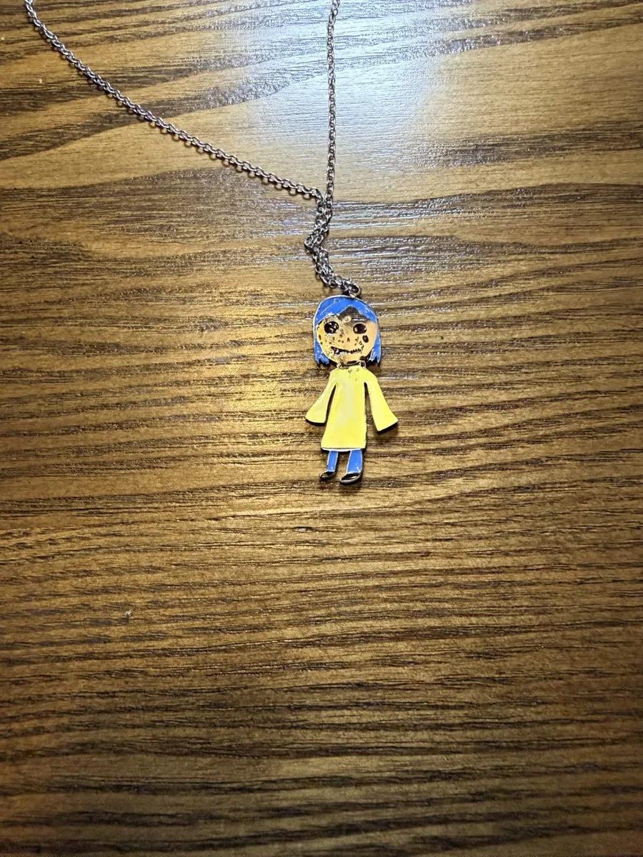 The full-colour necklace of the blue-haired girl in a yellow coat, on a wooden table
